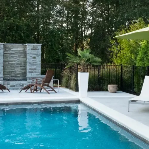 VESSEL pool with stacked-stone water feature wall and wood loungers